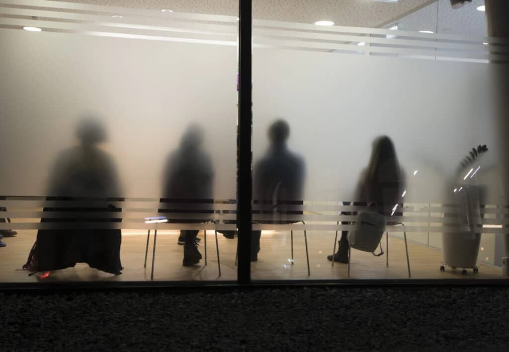rear view people sitting office seen from frosted glass wall@2x